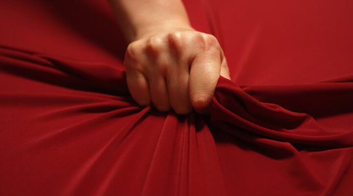 Empowering Women with Refined Companionship: Breaking the Stigmas 7 Woman hand passionately squeezes red bed sheet. Love concept.