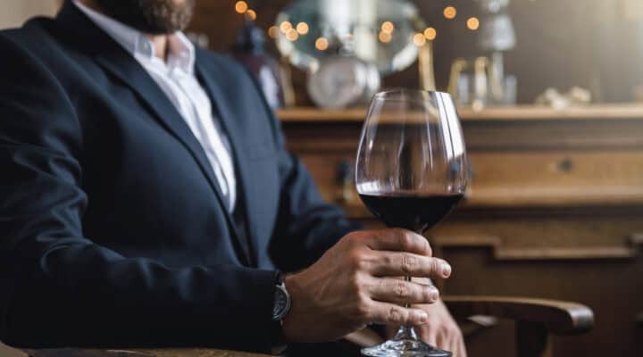 How to Book a Male Escort for Women: The Ultimate Guide for First Timers 5 Man wearing black suit with a glass of red wine