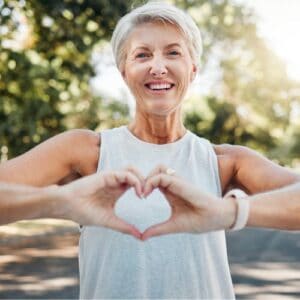 woman in her 50s doing a love heart with her hands