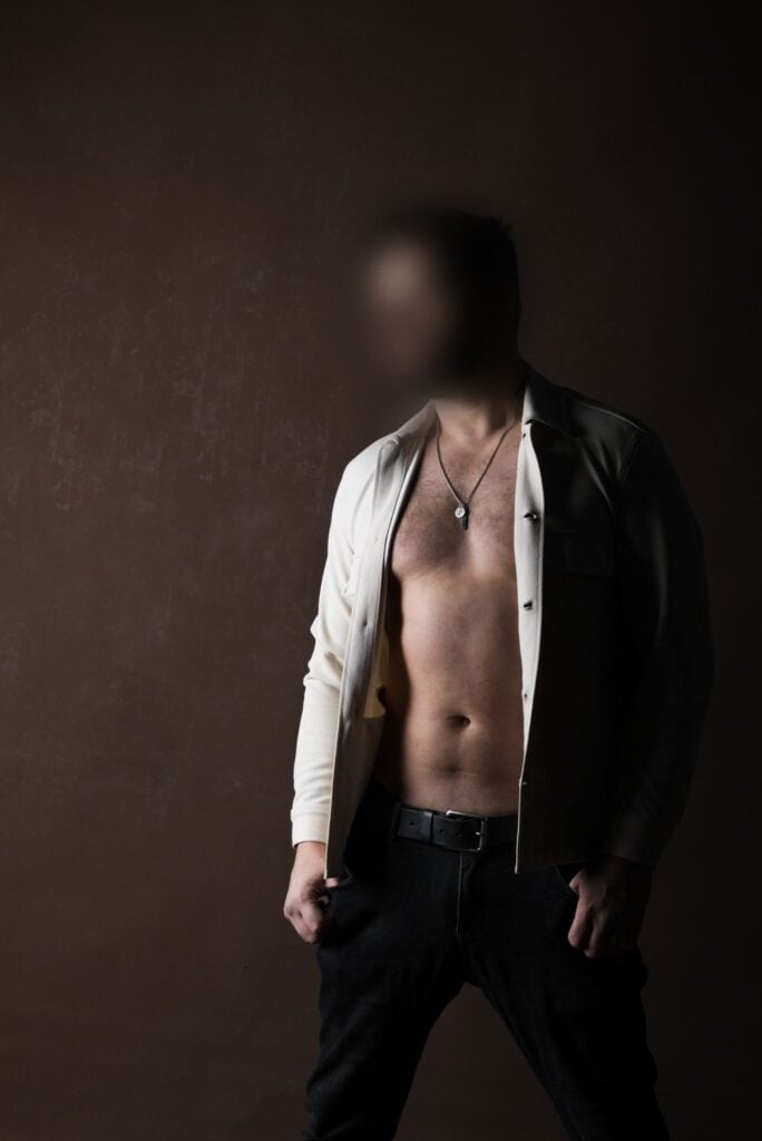 Male companion standing shirtless by the window, looking out thoughtfully