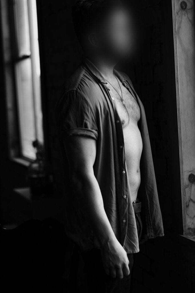 Male escort gazing out the window in natural light
