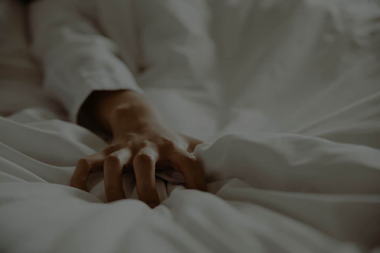Woman's hand grabbing white sheets in pleasure